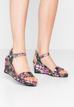 Kiilakorkosandaalit, joissa on monivärinen kukkakuvio ja matelijatulostetekstuuri. Säädettävä nilkkahihna, avoin varvasmuotoilu ja tukeva korko.