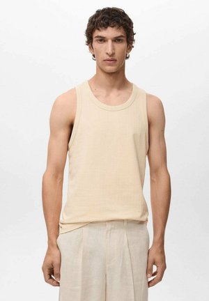 Beige ribbed tank top with a round neckline, made from soft textured fabric, paired with light-colored, relaxed-fit trousers.