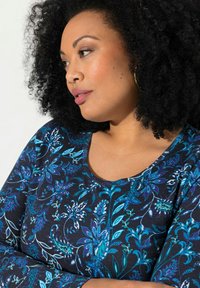 Lange mouwen shirt in donkerblauw met een ingewikkeld bloemenpatroon in verschillende tinten blauw. Heeft een ronde halslijn en een zachte, gestructureerde stof.