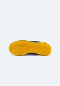Zapato azul con una parte superior texturizada y una suela de goma amarilla brillante que presenta patrones circulares y rayas horizontales para un mejor agarre.
