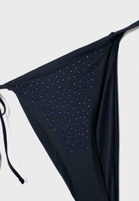 Bas de bikini noir avec des liens de chaque côté et de petits strass bleus disposés en un motif triangulaire dense sur un côté.