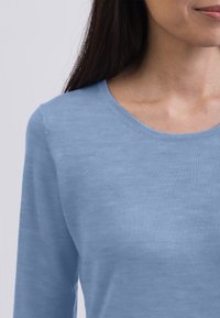 Himmelblaues Langarmhemd mit rundem Ausschnitt, aus weichem Stoff mit glatter Textur und minimalen Nähdetails gefertigt.