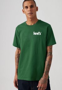 Tricou din bumbac verde, cu un logo alb "Levi's" pe partea stângă a pieptului. Mâneci scurte, gât rotund și o croială lejeră. Material texturat.