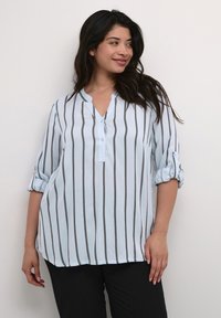 Blouse bleu clair avec des rayures verticales grises, décolleté en V et manches retroussables. Tissu lisse, coupe décontractée, adaptée aux temps chauds.