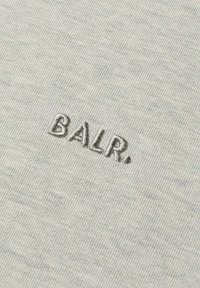 Tessuto grigio chiaro con un sottile motivo mélange, con il logo "BALR." ricamato in un filo grigio leggermente più scuro.