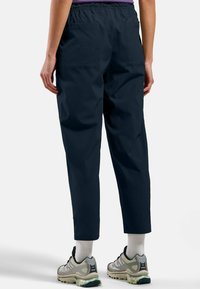 Marineblaue, leichte Cargo-Hosen mit einem elastischen Bund, zwei Gesäßtaschen und schmal zulaufenden Fesseln. Tragen mit Sportschuhen und weißen Socken.
