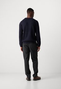 Navy knitted sweater with a round neckline, paired with gray tailored pants. The outfit includes brown shoes, well-fitted with a smooth texture.