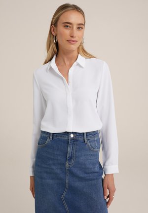 Witte blouse met lange mouwen van een gladde stof, met een knoopsluiting aan de voorkant en een standaard kraag, gecombineerd met een blauwe denim rok.