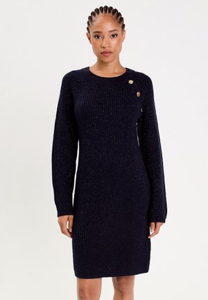 Robe en tricot navy à texture côtelée, avec des manches longues, un col rond et trois boutons dorés sur une épaule.