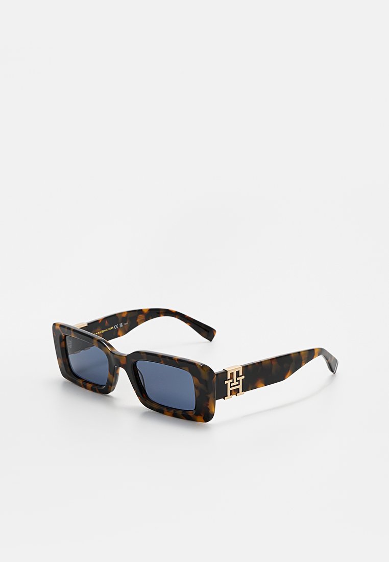 Lunettes de soleil en acétate avec un motif écaille de tortue, lentilles rectangulaires, teinte bleu foncé et finitions dorées avec un logo sur les branches.