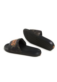 Svarta slip-in sandaler med ett mönstrat ovandel och orange "VANS"-text. Texturerade sulor ger bra grepp. Materialet verkar syntetiskt och flexibelt.