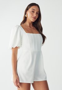 Witte playsuit met een vierkante halslijn, pofmouwen en verticale strepen op het lijfje. Gladde textuur en strakke silhoeet.