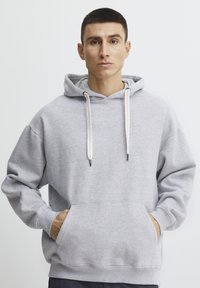 Gray hooded sweatshirt with a front pocket, drawstrings, and ribbed cuffs. Soft texture with a relaxed, oversized fit.