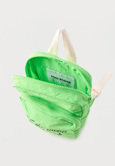 Mini zaino verde brillante con due scomparti con cerniera, manico bianco e etichetta "MINI RODINI" all'interno del compartimento principale aperto.