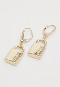Boucles d'oreilles dorées en forme de cadenas avec une finition polie. Présentent un fermoir à trombone et un détail gravé du logo.