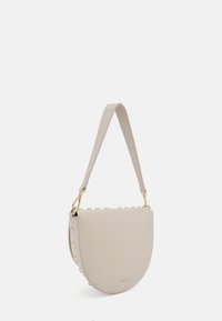 Sac à épaule en cuir beige avec une forme incurvée, accessoires en or et rivets décoratifs le long du bord supérieur. Bandoulière ajustable pour plus de confort.