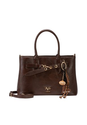 Donkerbruine leren handtas met dubbele hengsels, afneembare riem, gouden beslag en decoratieve sleutelhanger met een kleine voetbal en gevlochten detail.