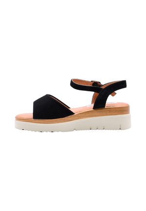 Sandalo nero con punta aperta, cinturino alla caviglia, intersuola piattaforma in legno e suola in gomma bianca con battistrada, visto di lato su sfondo bianco.