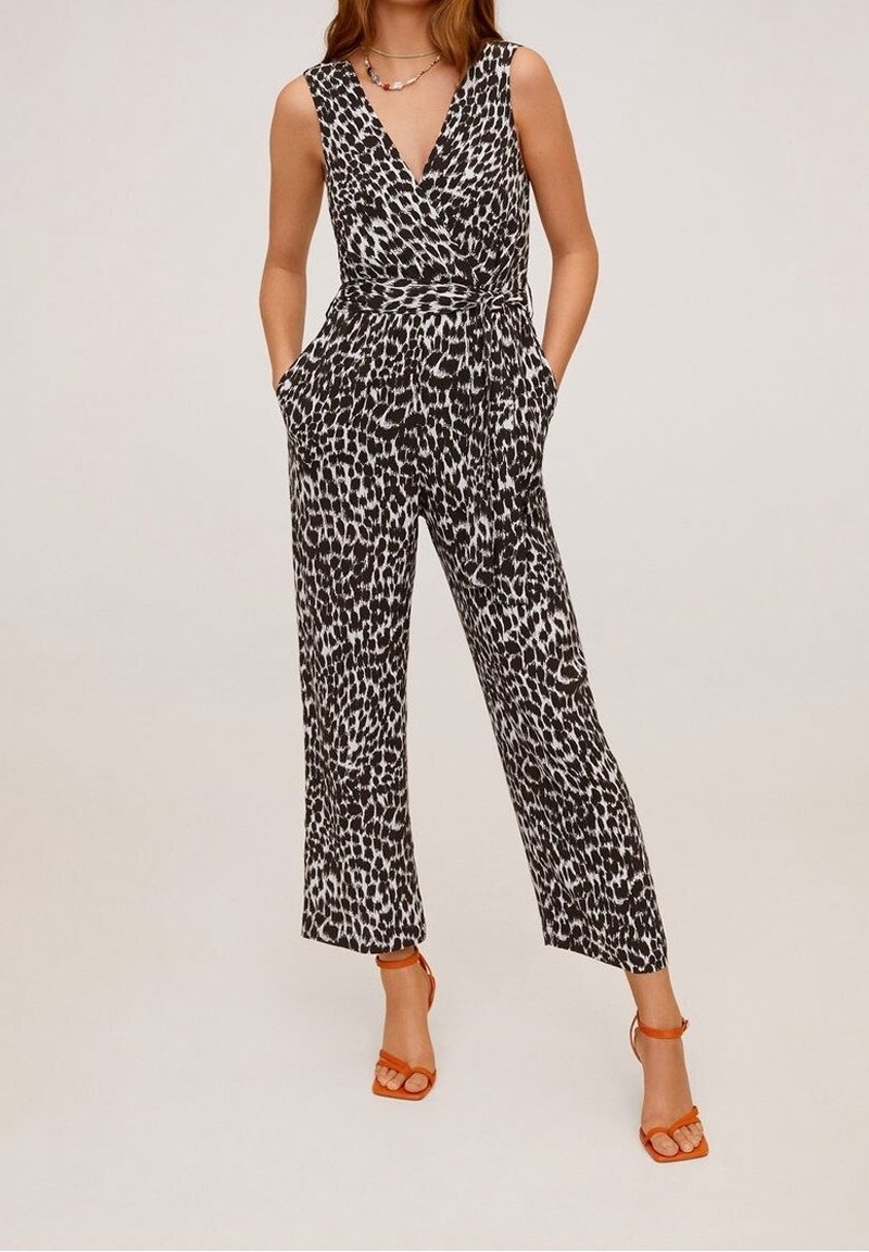 Mono de patrón en blanco y negro con escote en V profundo, cintura ajustada, piernas anchas y bolsillos laterales, combinado con sandalias de tacón naranja.