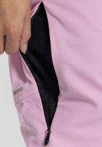Ljusrosa tyg med en svart meshficka. Fickan har en dragkedjestängning och texten "S8000" broderad nära sömmen.