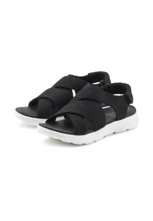 Black woven sandals with a crisscross strap design, featuring a textured upper and white rubber sole. Open-toe style for breathability.