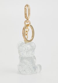 LKeychain cu un ursuleț din rășină transparentă cu un finisaj lucios, având sclipici și accesorii aurii pentru atașare.