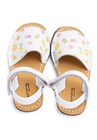 Sandalias de cuero blanco con un colorido patrón de frutas y helados, diseño de punta abierta, correas ajustables y una plantilla de cuero marrón.