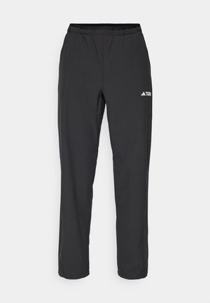 Pantalons de sport noirs avec un waistband élastique, des jambes droites et un petit logo blanc sur le côté gauche. Fabriqués en tissu léger.
