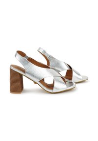 Zilveren metallic hoge hak sandalen met een kruisriemontwerp, open teen en een blokhak met een gestructureerd houtpatroon. Verstelbare gesp.