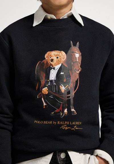 Granatowa bluza z grafiką niedźwiedzia w smokingu obok konia. Charakterystyczne detale to zegarek, poszetka i kontrastujący kołnierz koszuli.