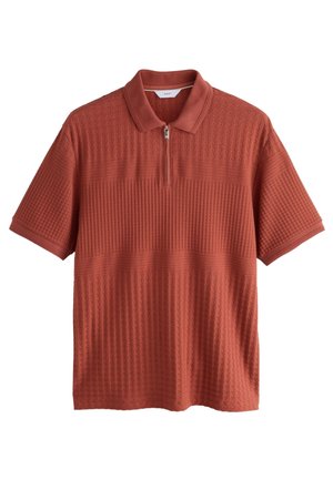 Rust-orangefarbenes kurzärmeliges Poloshirt mit strukturiertem Strickmuster und einem halbzippkragen, flach auf weißem Hintergrund dargestellt.