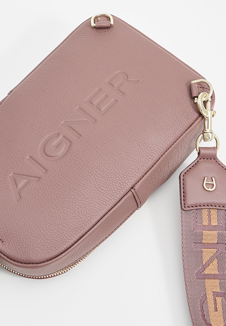 Rosa Leder-Umhängetasche mit geprägt Logo, goldenen Hardware und einem abnehmbaren Riemen mit einem gemusterten Textil. Glatte Oberfläche und runde Form.