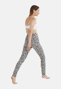 Leggings en imprimé léopard en blanc avec des taches noires et brunes. Le design présente une coupe ajustée et une taille élastique.