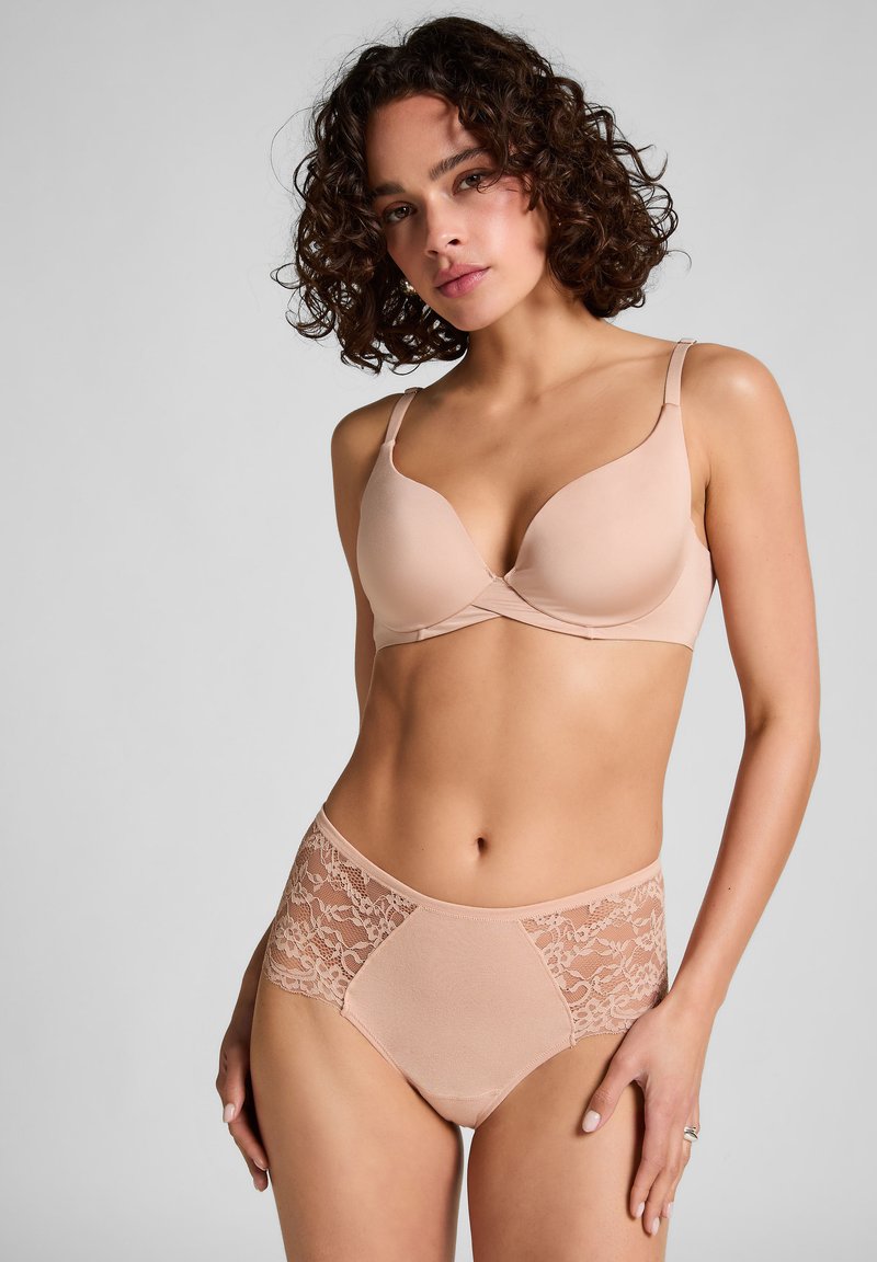 Beige beha met gladde, gevormde cups en een decoratief kruisontwerp. Bijpassende high-waisted slip met kantinzetstukken aan de zijkanten.
