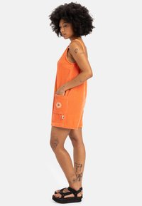Oranje, geribbeld stoffen romper met brede bandjes, zijzakken en bloemendetail borduurwerk. Heeft een losse, comfortabele pasvorm en een zoom boven de knie.