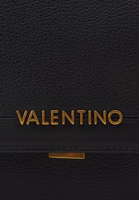 Svart lærveske med teksturert overflate, gull "VALENTINO"-logo og metallisk detalj nær bunnen. Rektangulært design.