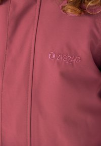 Wijnkleurige jas gemaakt van gladde stof, met een tonale geborduurde "ZIGZAG"-logo en strakke lijnen met subtiele stiknaden accenten.