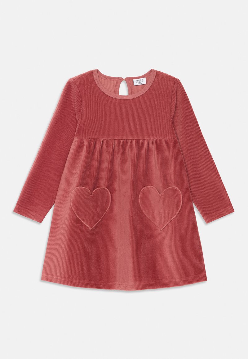 Vestido de pana rojo con mangas largas, escote redondo y espalda con abertura en forma de llave. Presenta dos bolsillos en forma de corazón con detalles de costura.