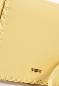Borsa a mano gialla in pelle con accenti intrecciati, una texture liscia e una placca con logo dorato, che presenta un design compatto.