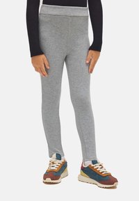 Leggings grises hechos de una suave tela de mezclilla de algodón, con una cinturilla ancha y cómoda y un diseño ajustado. Combinados con zapatillas de colores.