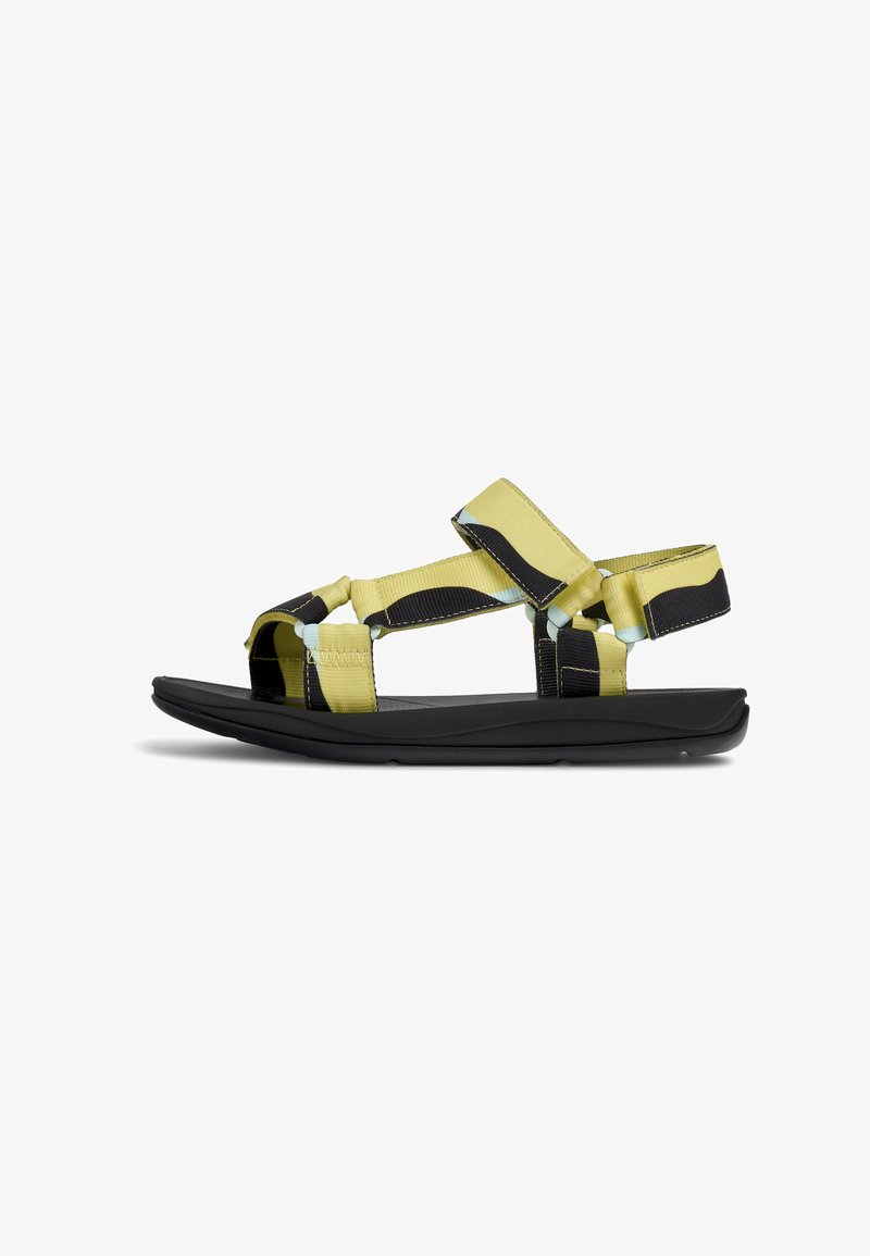 Sandal dengan tali yang terbuat dari kain kuning dan hitam, penutupan Velcro yang dapat disesuaikan, serta sol karet hitam dengan desain terkontur.