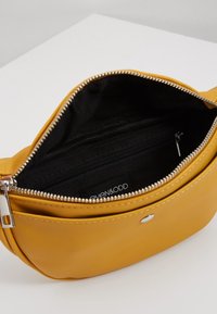 Borsa in ecopelle gialla con chiusura a zip, dotata di interno nero e una piccola tasca con zip. Dettagli in metallo color argento.