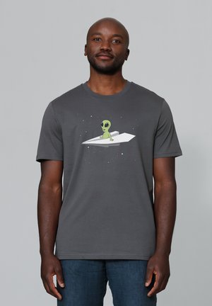 Grijze katoenen T-shirt met een groene alienafbeelding op een witte papieren vliegtuig met sterren op de achtergrond. Korte mouwen, ronde hals ontwerp.