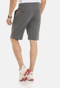Graue Shorts mit bequemer Passform, ausgestattet mit einem Kordelzugbund und zwei Gesäßtaschen. Hergestellt aus einem weichen Stoff mit glatter Textur.