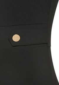 Crni materijal s glatkom teksturom, s dekorativnim dugmetom zlatne boje na bočnom preklopu, što stvara moderan, strukturiran dizajn.