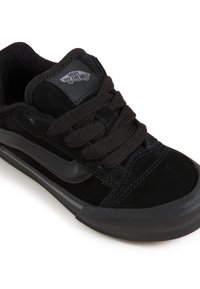 Sneaker in suede nero con suola in gomma nera testurizzata, design con lacci e logo Vans sulla linguetta. Presenta dettagli cuciti e una striscia accentuata liscia.