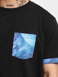 Black t-shirt made of cotton, featuring a blue patterned pocket and matching accents on the sleeves. Short sleeves, crew neck design.
