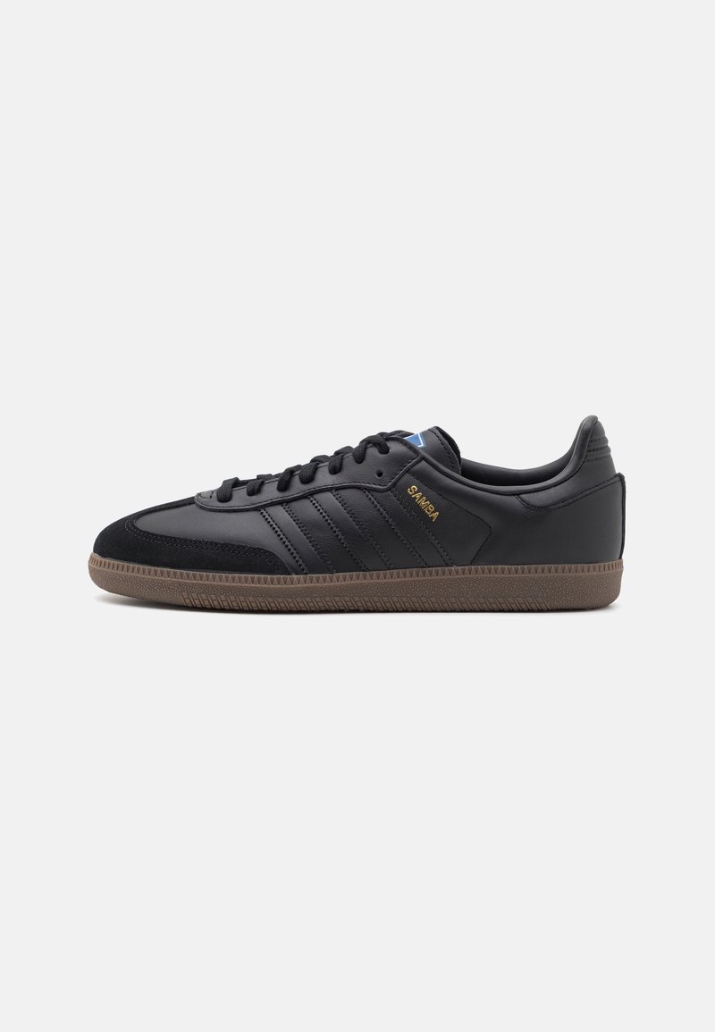 Schwarzer Ledersneaker mit drei schwarzen Streifen, Wildlederakzenten und brauner Gummisohle. Verfügt über ein Schnürdesign und ein goldenes Logodetail.