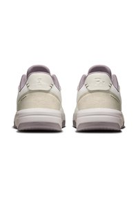 White sneakers with a textured beige panel, lavender accents, padded collar, and logo detail on the heel. Rubber sole with grip patterns.