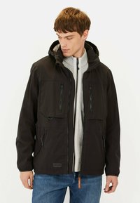 Veste noire imperméable avec capuche, fermeture éclair frontale, plusieurs poches zippées, tissu texturé et accents de fermeture éclair contrastants.
